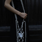 Sparkly silver wine tote bag with knotted design, held by woman in black dress for elegant wine gifting.
